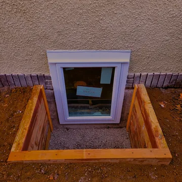 Timber egress window well with Andersen casement window against stucco exterior — Twin Cities Metro MN